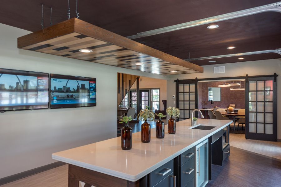 Attain on 5th apartment homes with Modern kitchen with a large island, pendant lights, TVs on the wall, and sliding glass doors to a dining room.