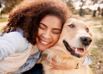 Attain on 5th apartment homes with Woman smiling and hugging a happy golden retriever outdoors in a sunny park.