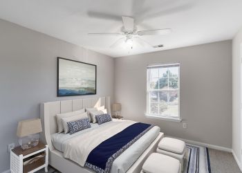 Attain on 5th apartment homes with A bright bedroom with a bed, artwork above the headboard, and sunlight coming through a window.