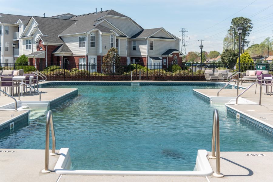 Attain on 5th apartment homes with Outdoor apartment pool with steps, surrounding deck chairs, and residential buildings in the background.