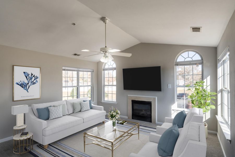 Attain on 5th apartment homes with Bright living room with white sofas, a glass coffee table, a TV above a fireplace, and large windows.