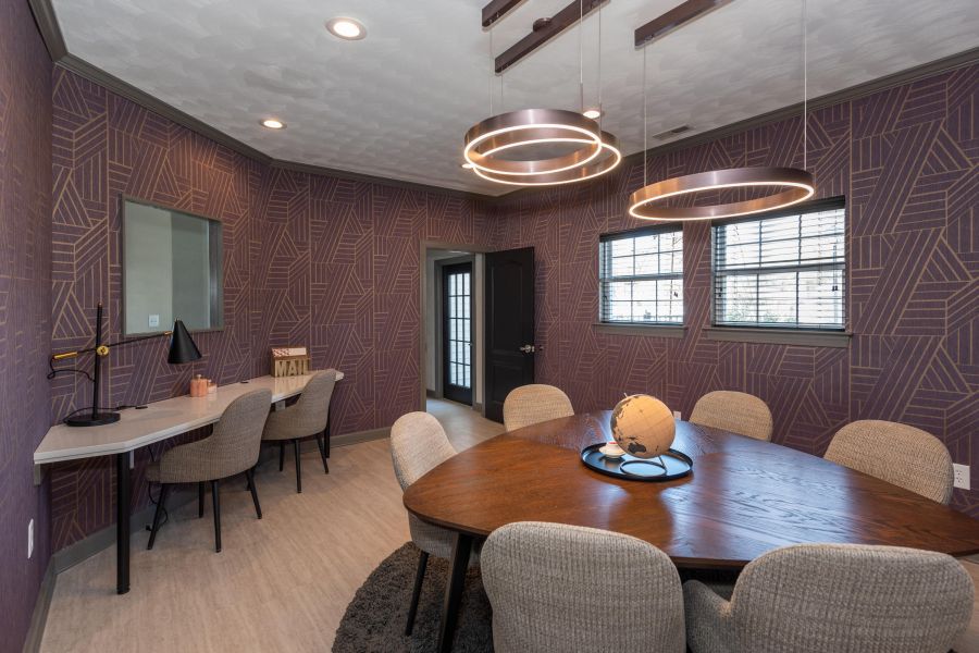Attain on 5th apartment homes with Modern dining room with geometric wallpaper, oval wooden table, beige chairs, and circular pendant lights.